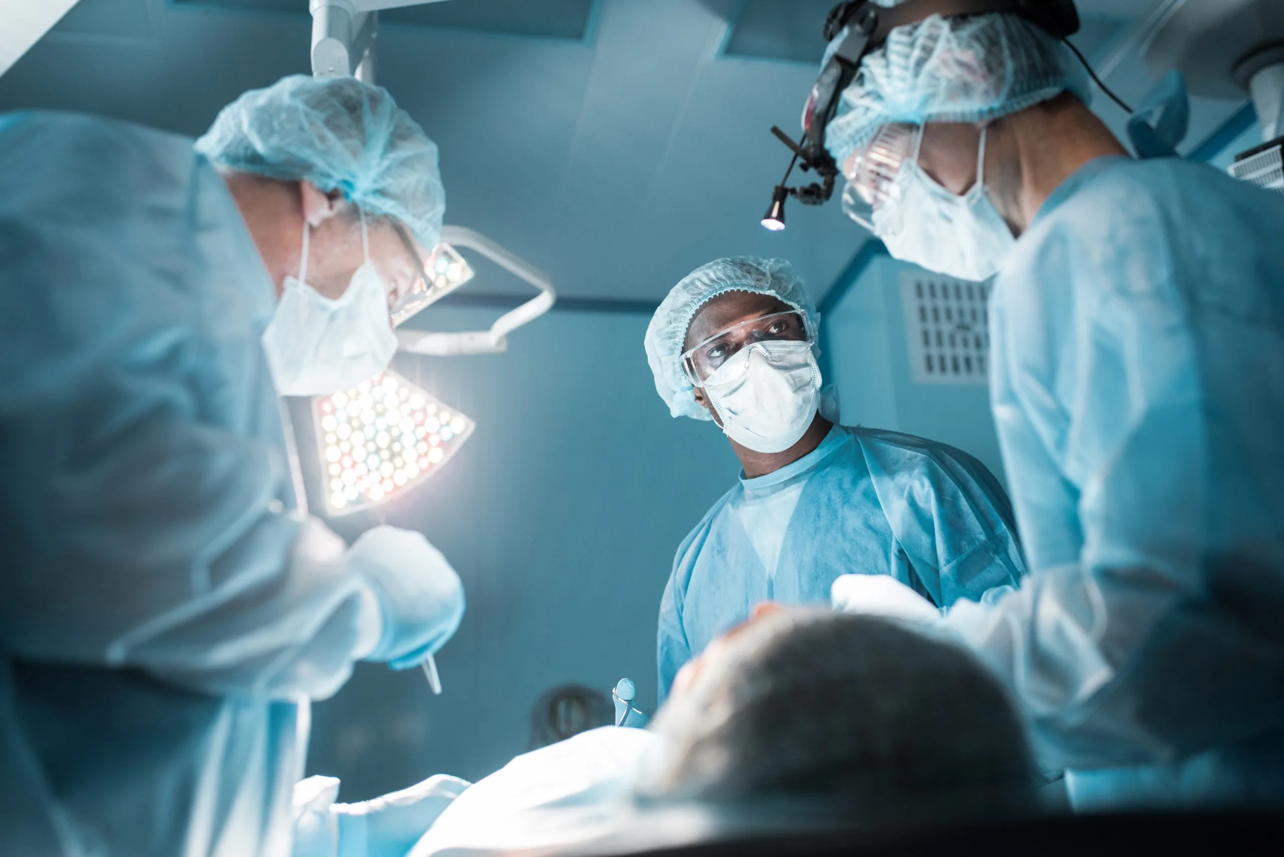bottom view of multicultural surgeons operating patient in operating room