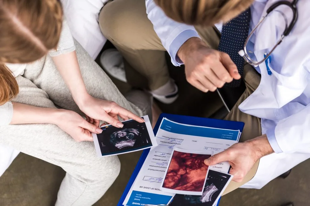Cropped shot of doctor and woman looking at ultrasound scans