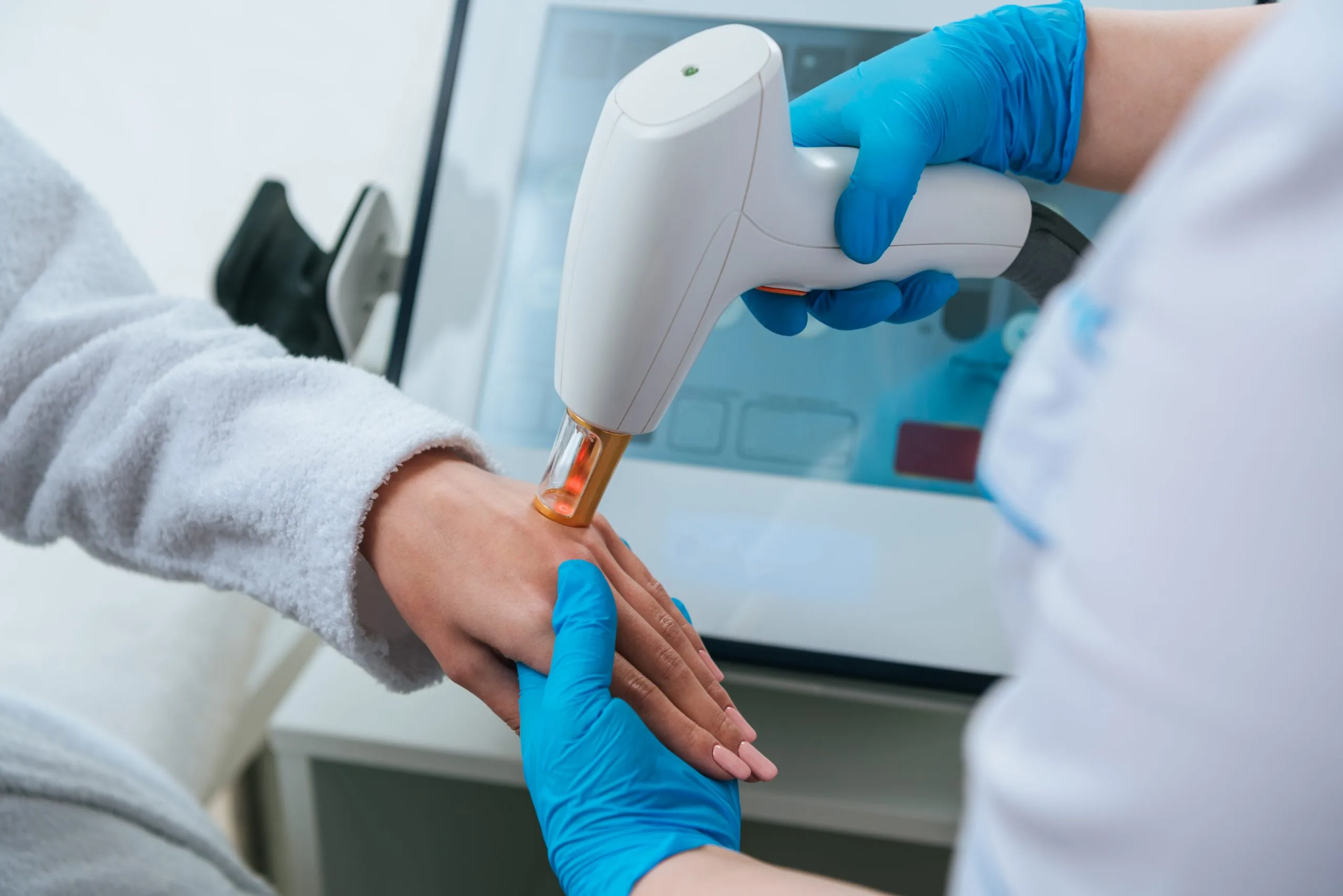 Cropped view of cosmetologist doing laser hair removal procedure on hand