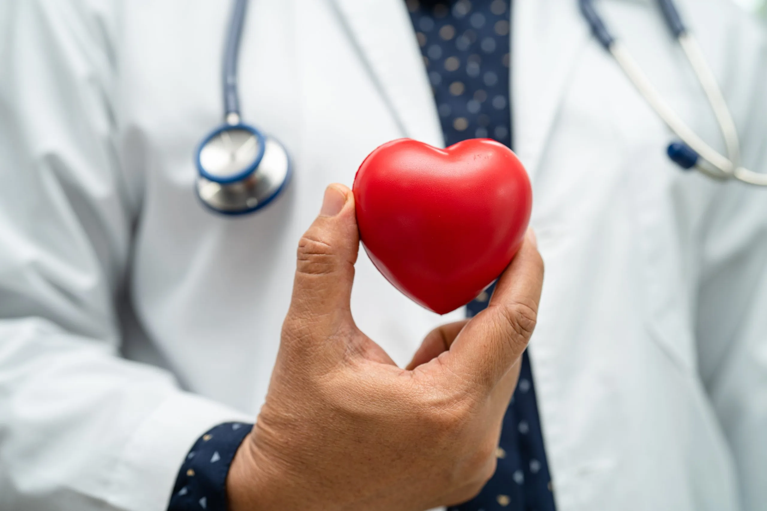 Doctor holding a red heart in hospital ward, healthy strong medical concept.