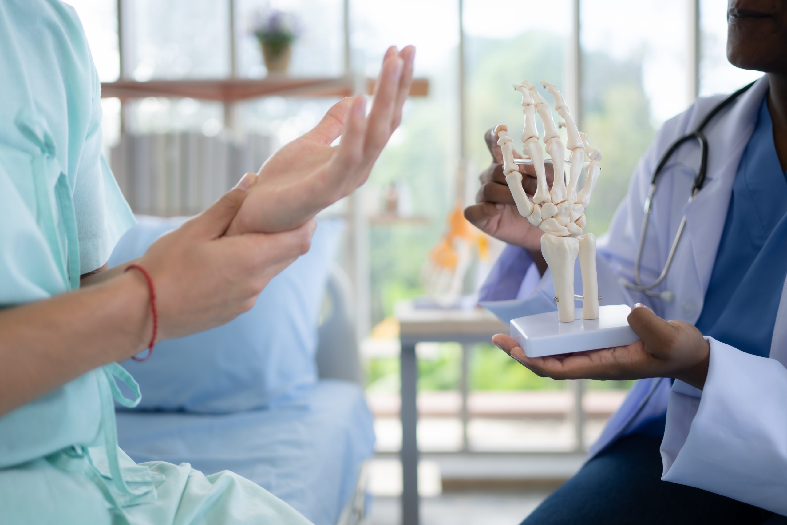 Doctor showing model of finger bones to patient in hospital. Medical and healthcare concept.