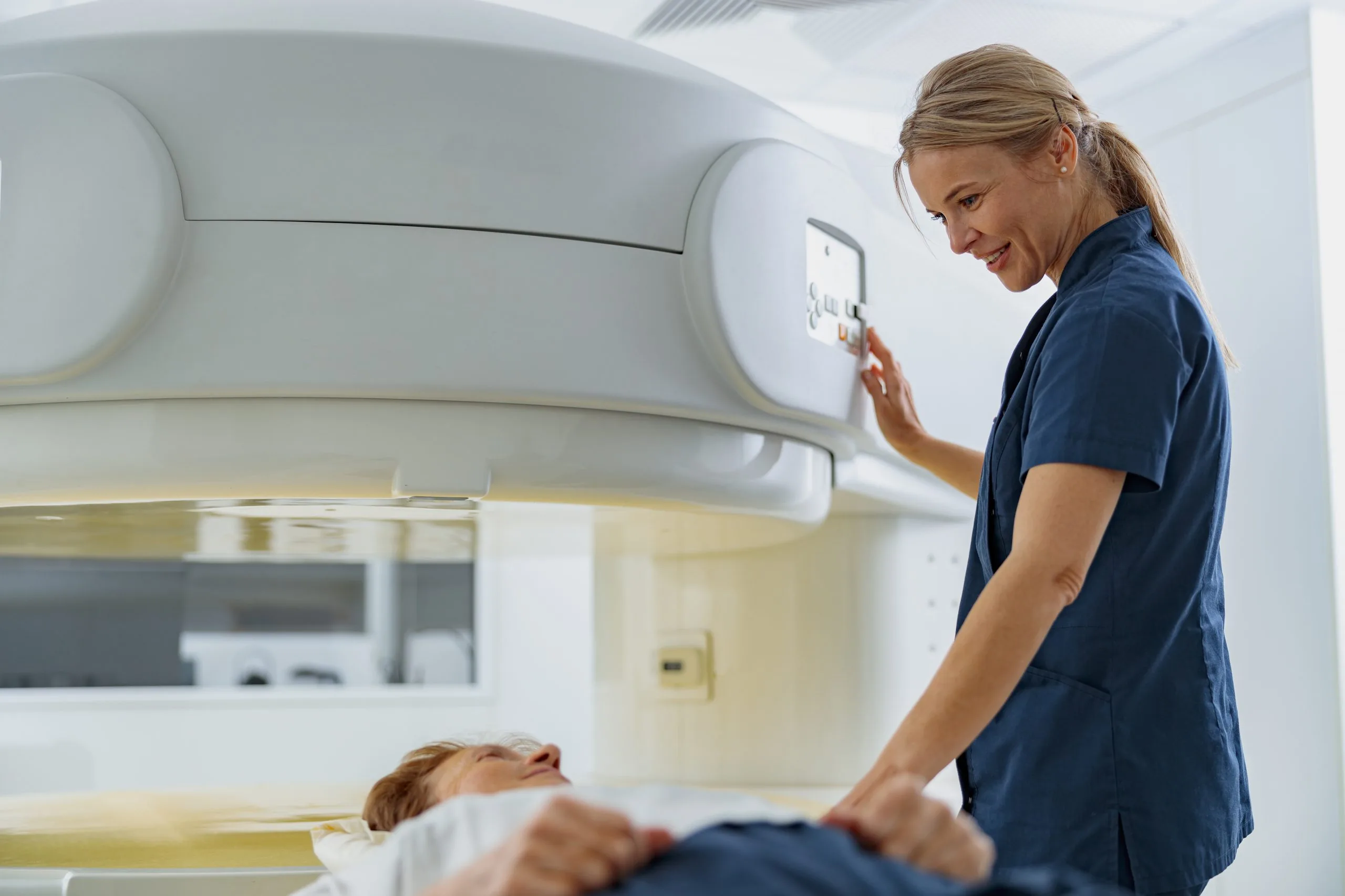 Radiologist controls MRI or CT Scan with patient undergoing procedure. High Tech medical equipment