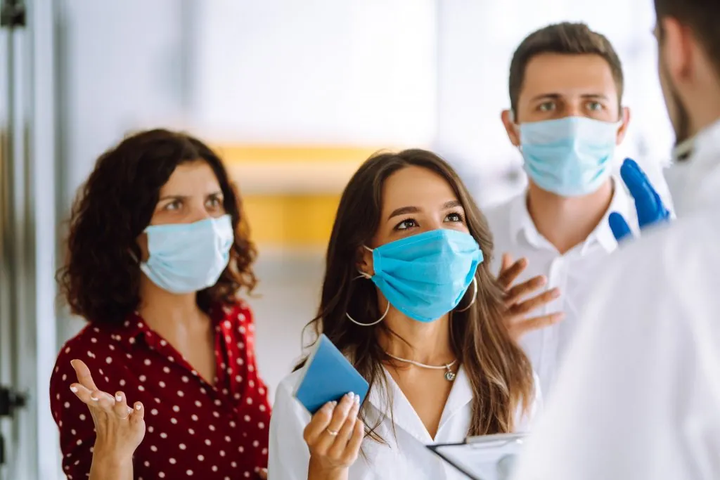 ?rowd of people in medical masks at the entrance to the office. The concept of preventing the spread