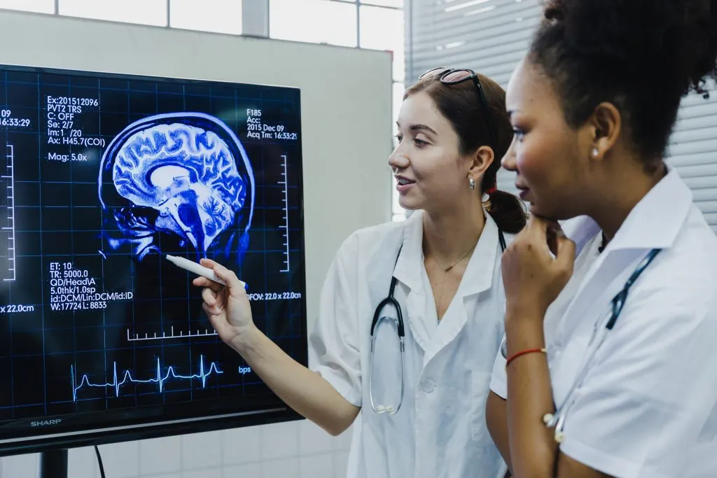 Team of female doctor check on scan results paper and looking at monitors in laboratory and plan and share medical knowledge and experience benefits her coworkers and patients