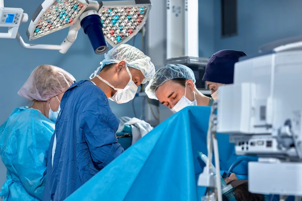 The team of surgeons in the operating room bent over the patient, complex surgical operation, high-tech medicine, life saving.