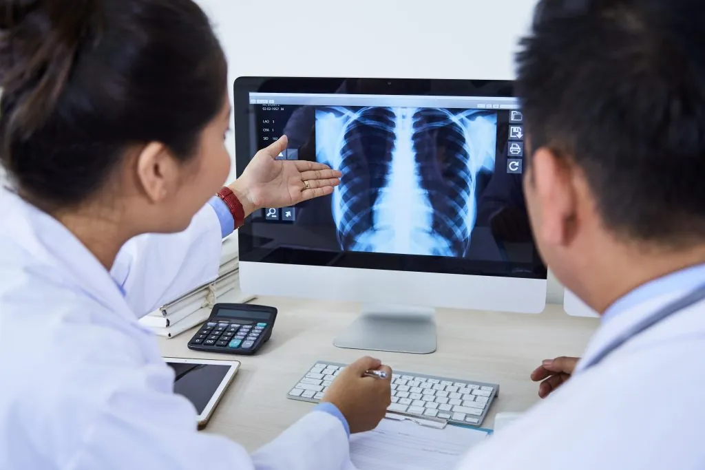 Two unrecognizable pulmonologists working together on mediacal case looking at X-ray image